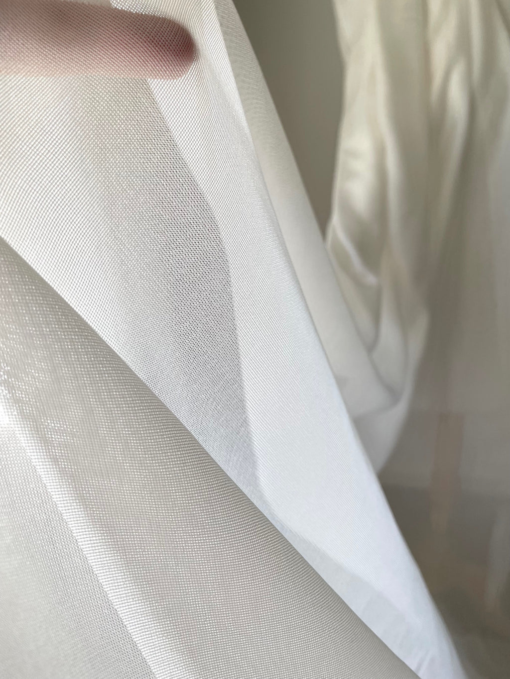 Close-up of sheer white silk mesh fabric with a blurred background