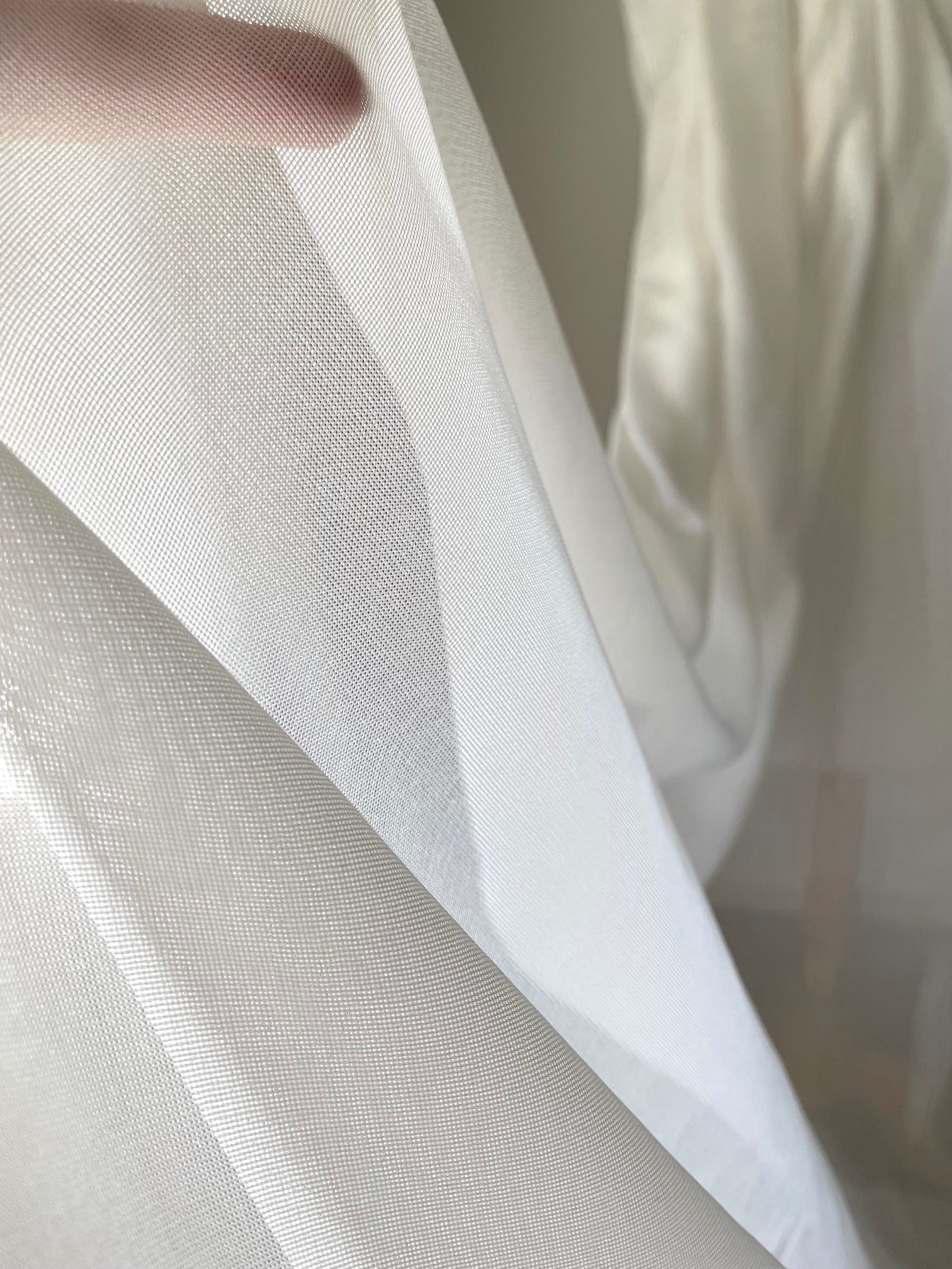 Close-up of sheer white silk mesh fabric with a blurred background