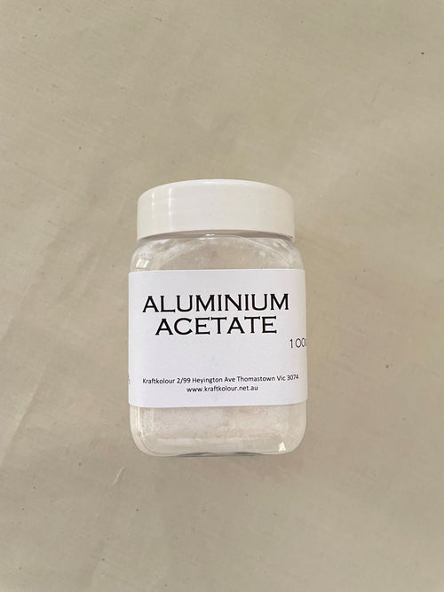 Small plastic container labeled 'Aluminium Acetate' on a beige background