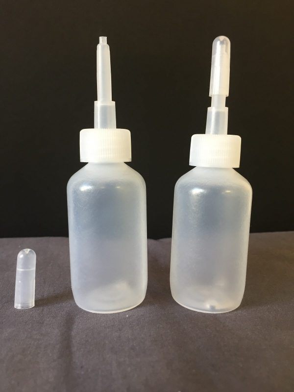 Two clear plastic dropper bottles with white caps on a dark surface.