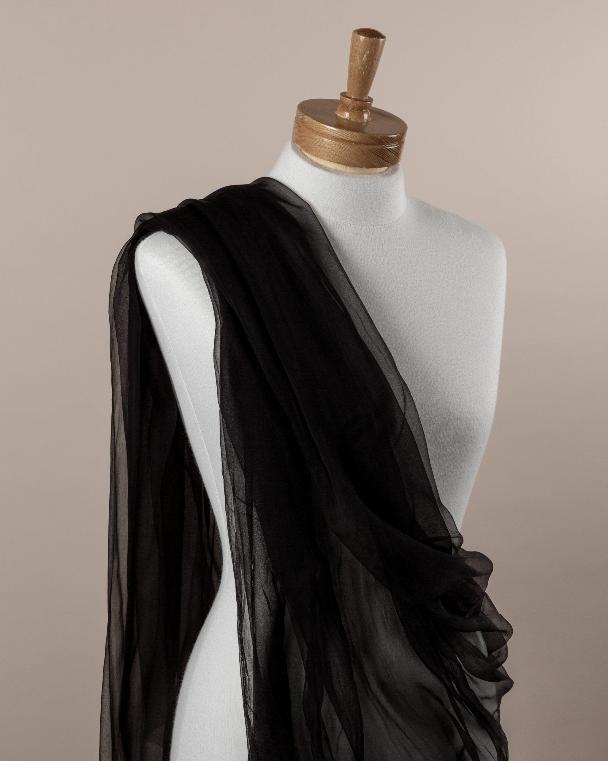 Black silk gauze fabric draped over a mannequin on a beige background