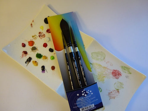 Set of watercolor brushes and swatch cards on a white surface