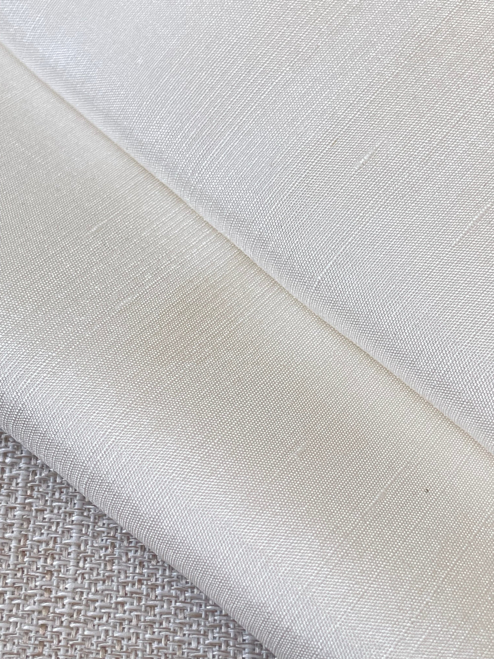 Close-up of undyed silk dupioni fabric with a textured pattern on a neutral background