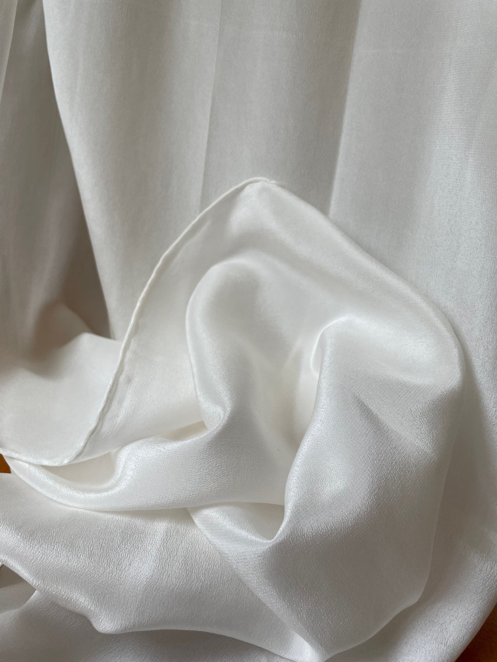 Close-up of crumpled undyed white crepe de chine silk fabric with folds