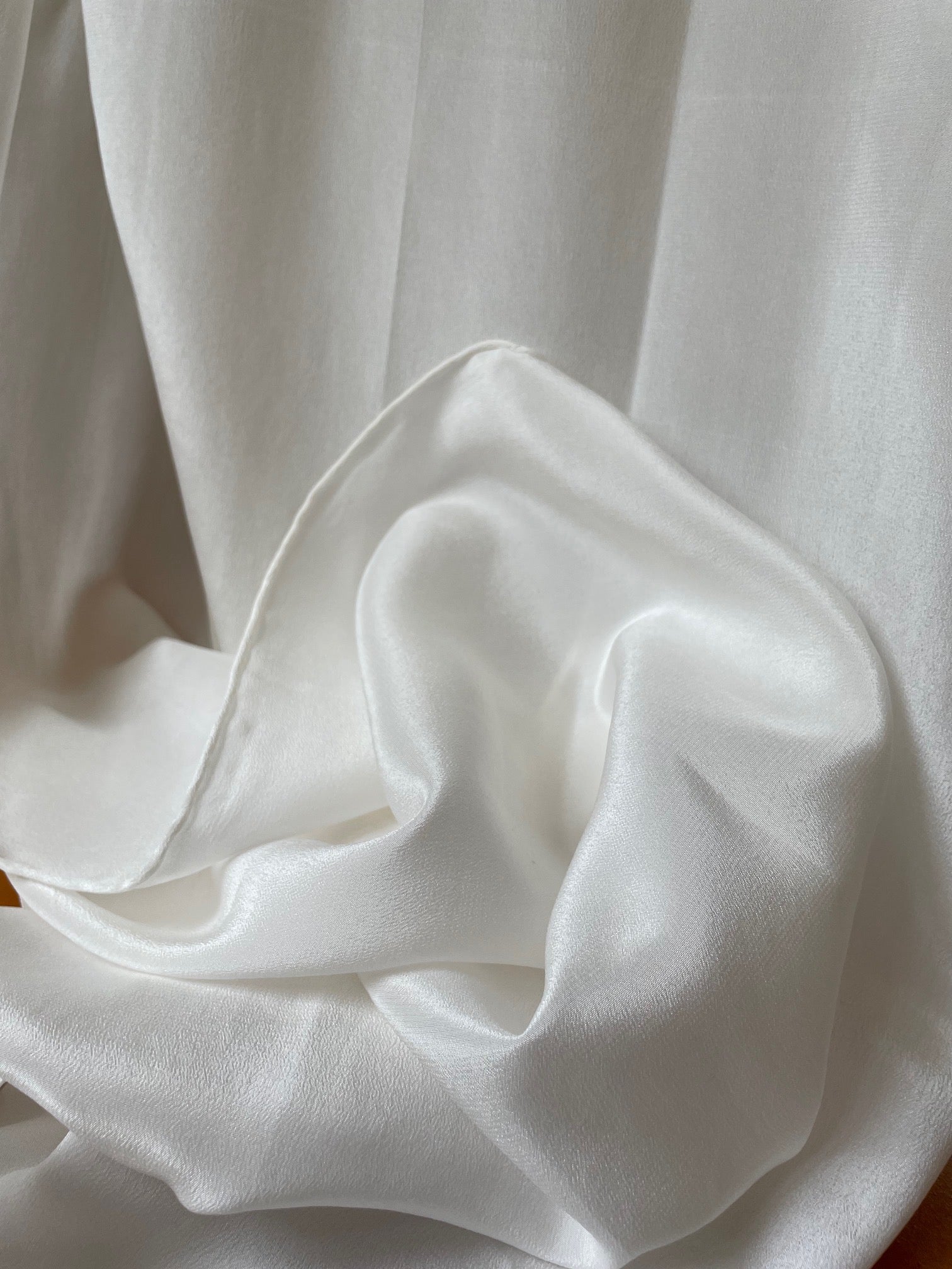 Close-up of crumpled undyed white crepe de chine silk fabric with folds