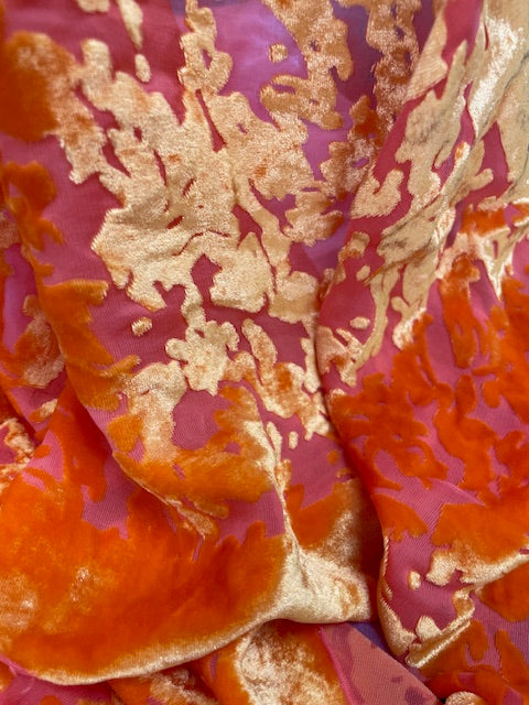 Close-up of fabric with gold and orange floral pattern on a pink background