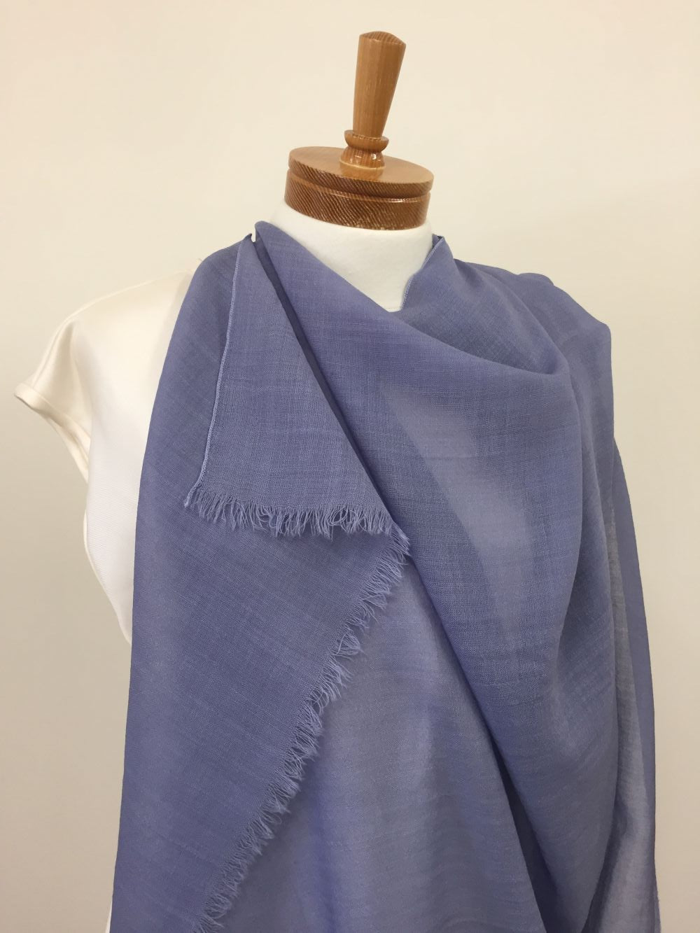 Dyed Blue wool gauze fabric draped over a mannequin against a beige background