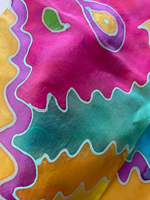 Close-up of colorful H Dupont silk dyes painted on silk fabric with wavy patterns in pink, green, orange, and purple.