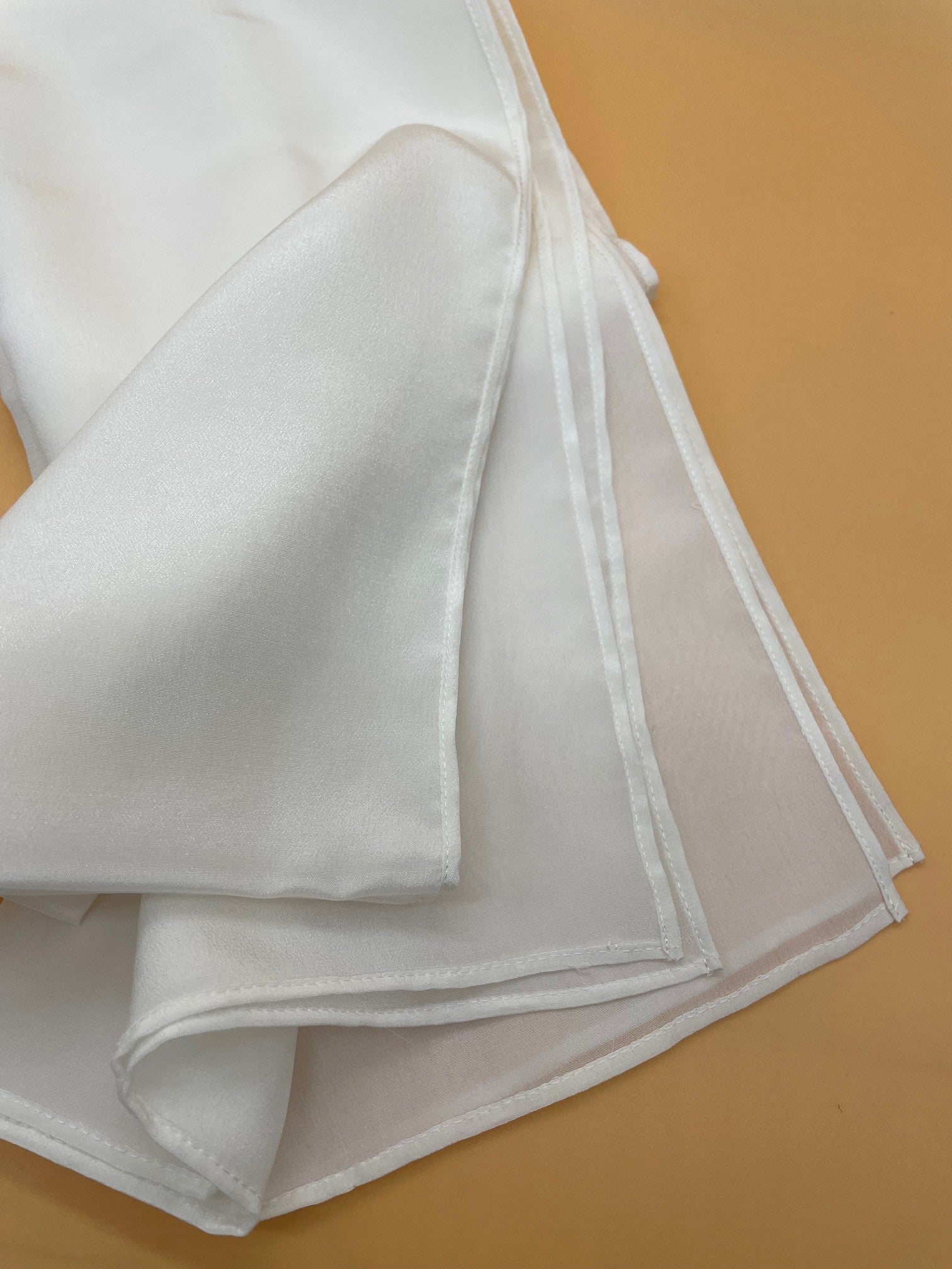 Undyed white crepe de chine scarf on a brown surface