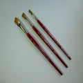 Three paintbrushes with red handles and gold ferrules on a white background