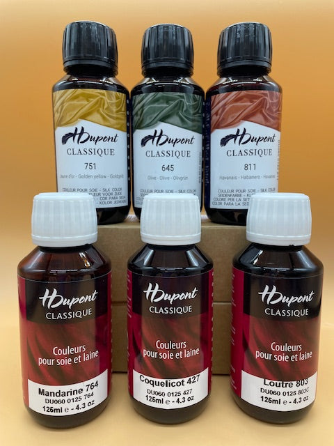 Six bottles of H Dupont Classique silk dyes on a gradient background