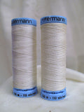 Two spools of Gutermann thread on a white background