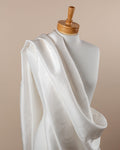 Undyed silk dupioni fabric draped over a mannequin on a beige background