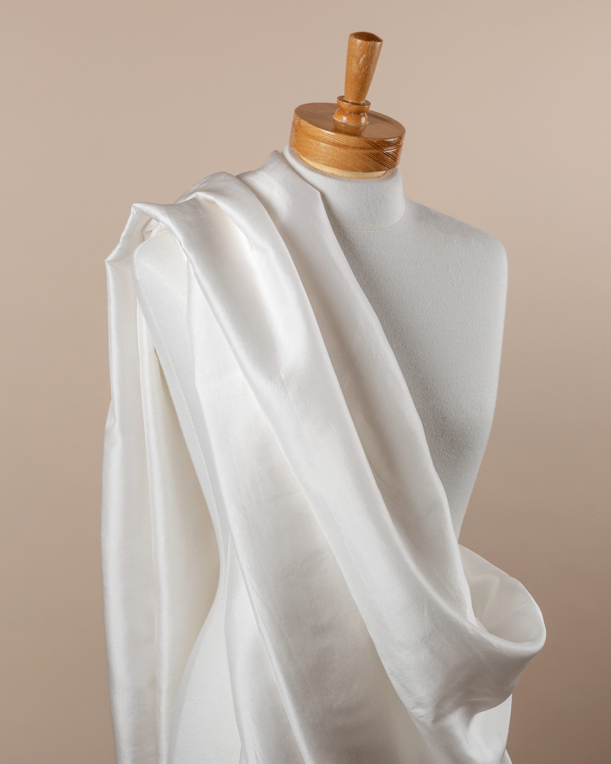 Undyed silk dupioni fabric draped over a mannequin on a beige background