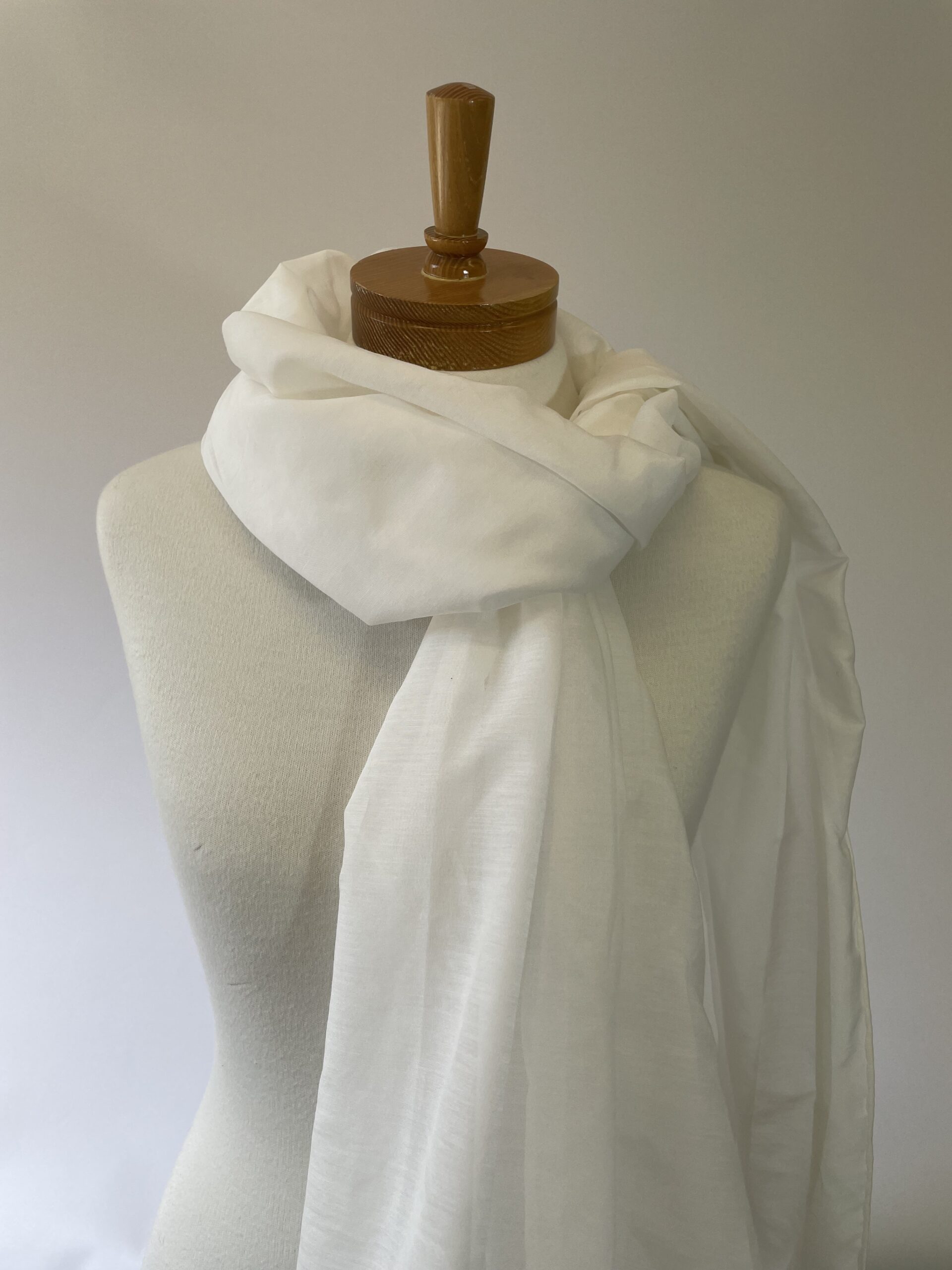 Undyed silk cotton scarf draped over a mannequin with a wooden head on a plain background