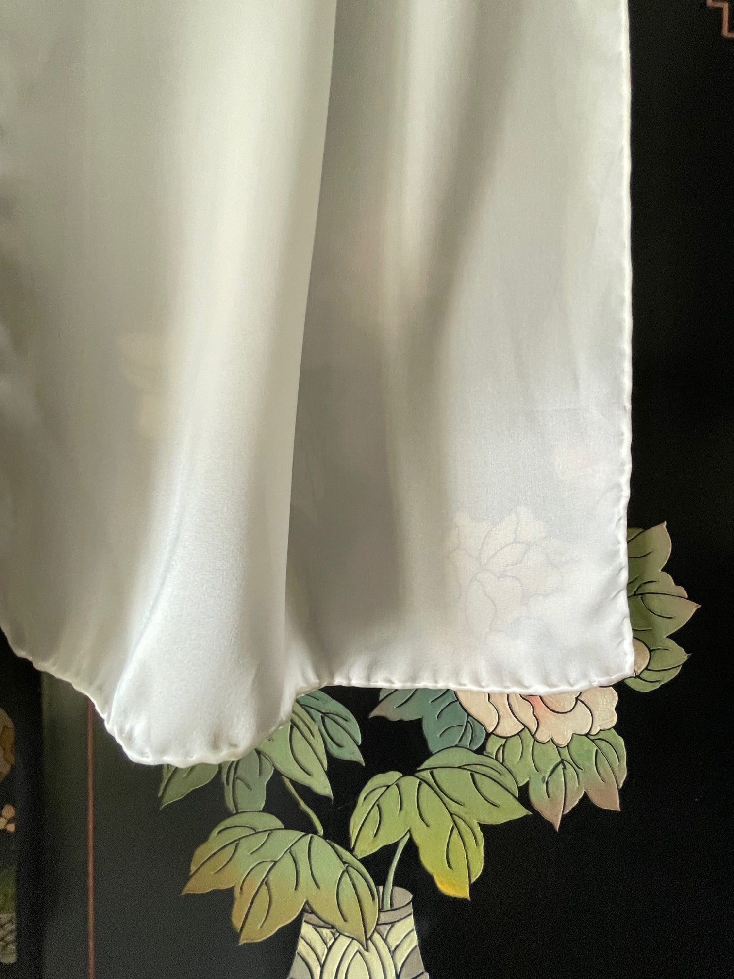 Undyed White silk satin crepe scarf on a dark surface with floral patterns