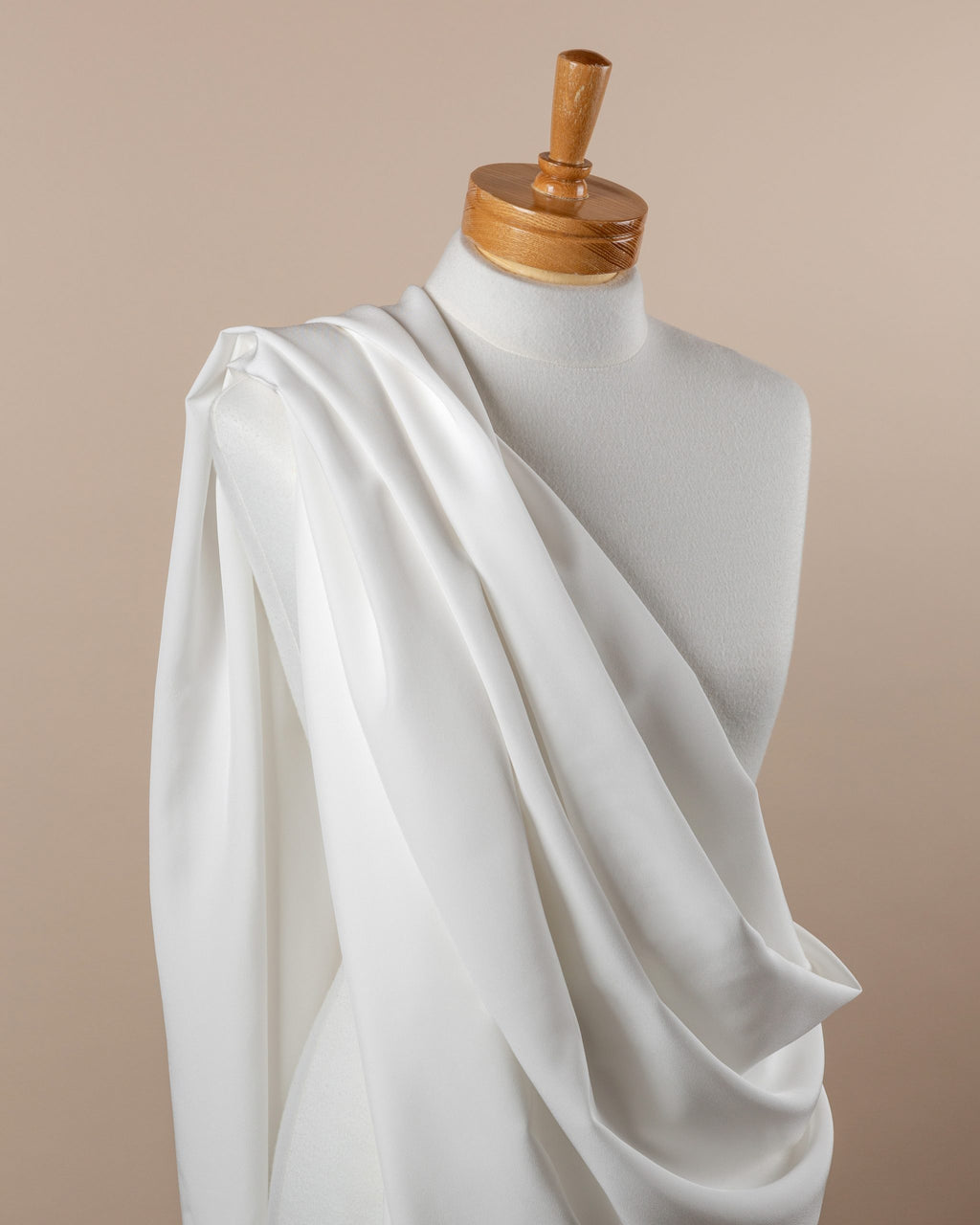 Undyed White crepe de chine silk fabric draped over a mannequin on a beige background