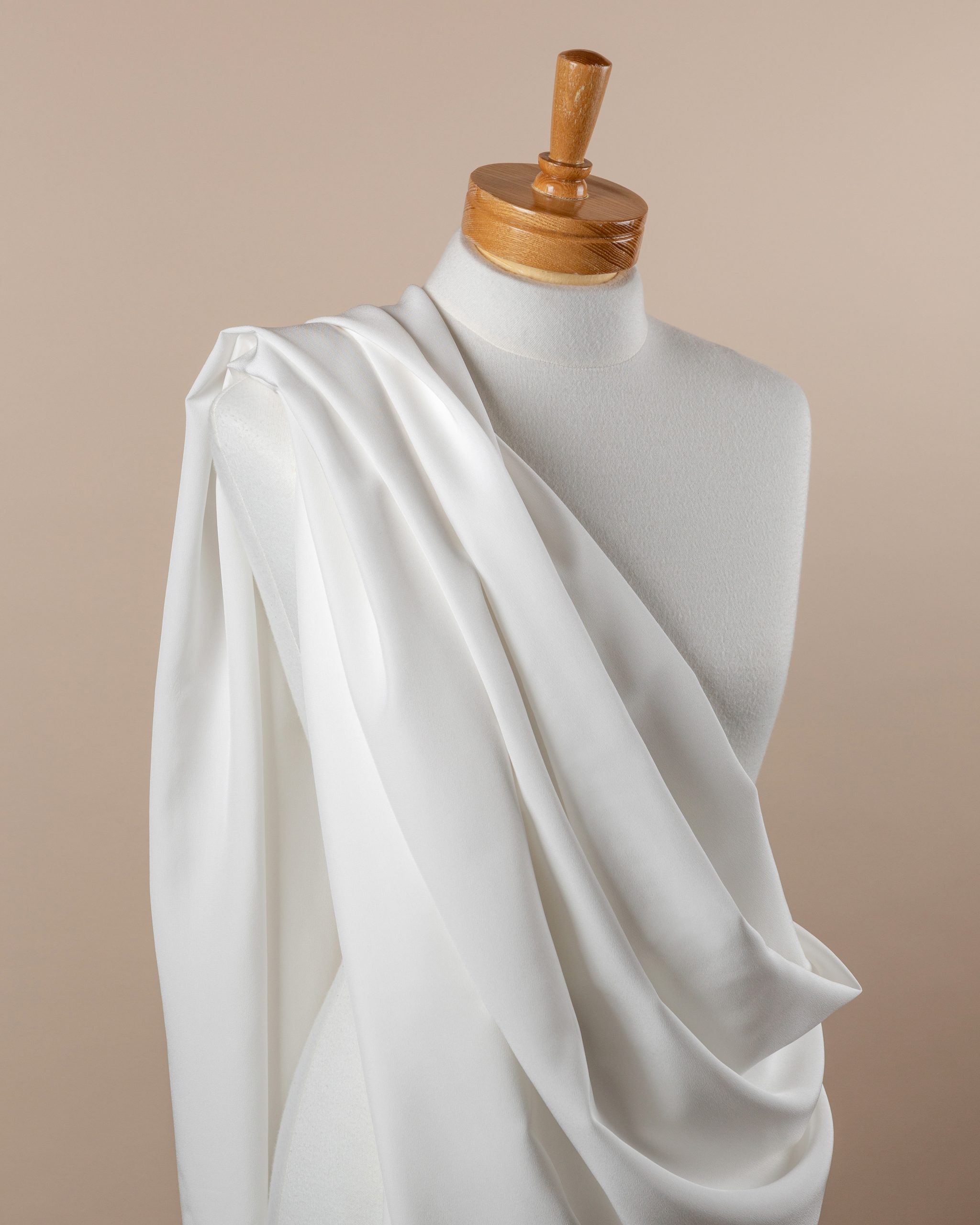 Undyed White crepe de chine silk fabric draped over a mannequin on a beige background