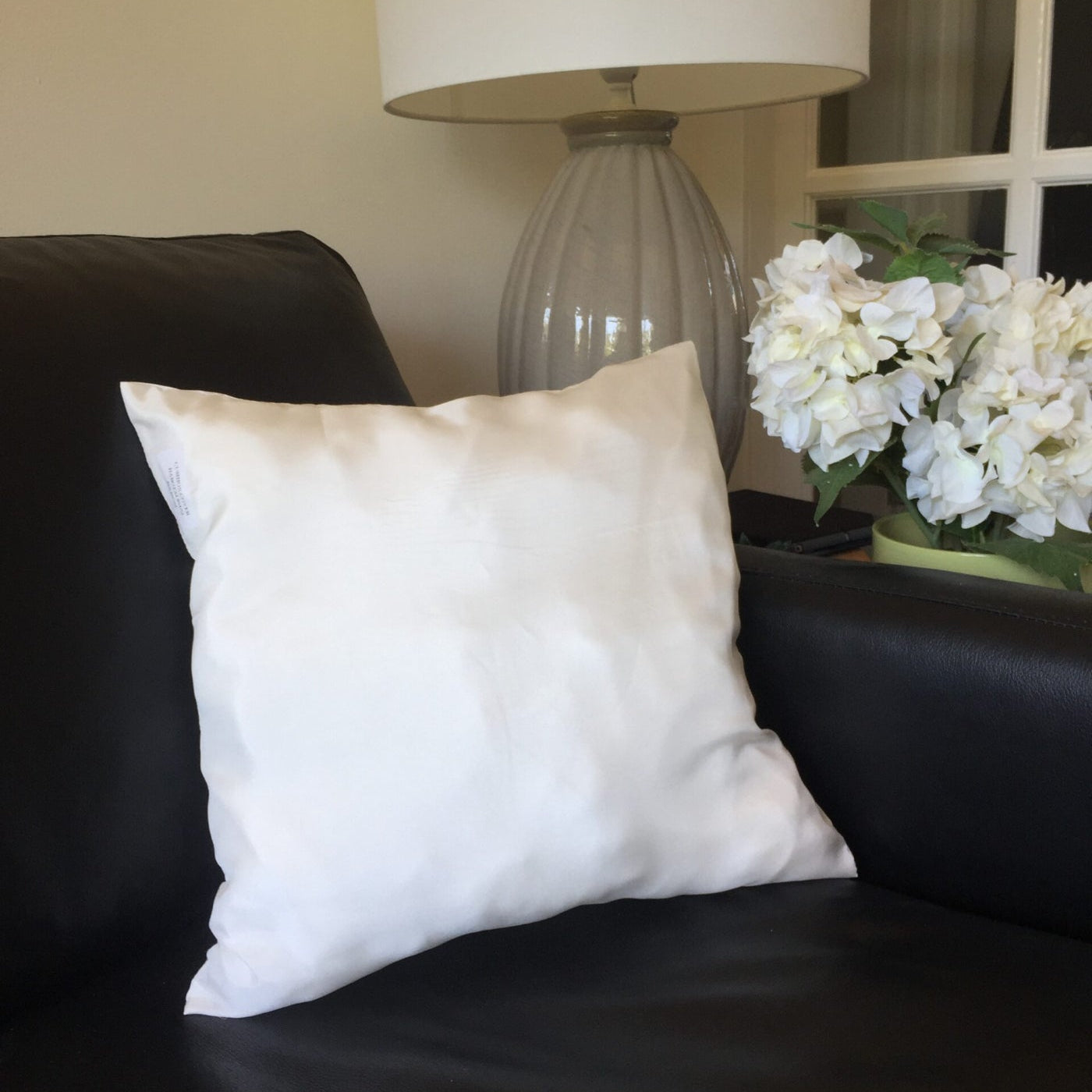 Undyed Habutai on a black couch with a lamp and flowers in the background