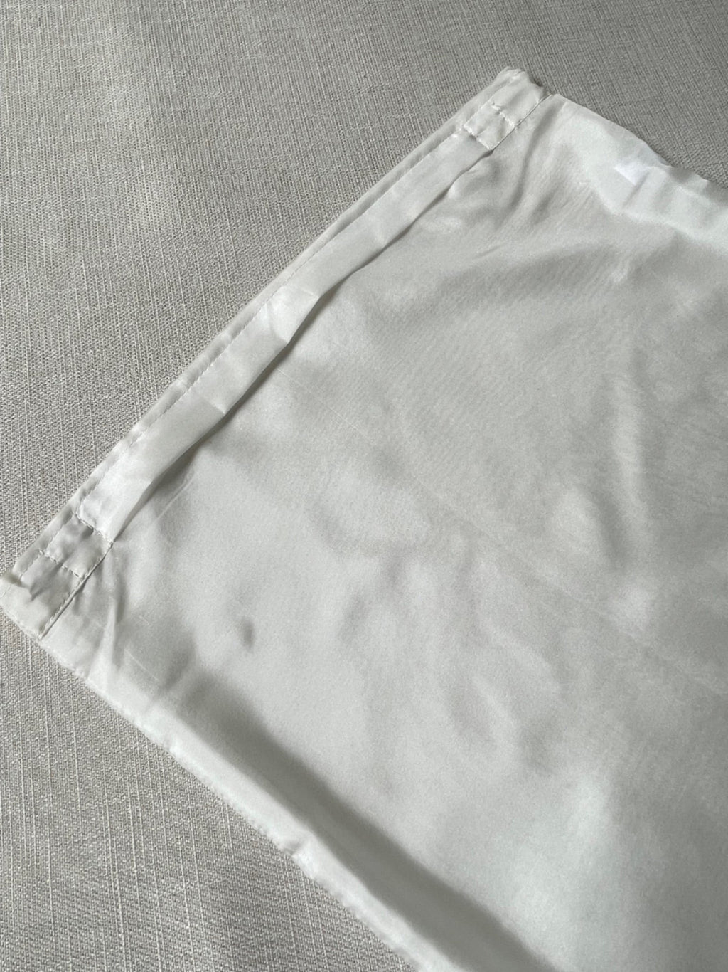 Undyed Habutai cushion cover zip section on a gray textured surface
