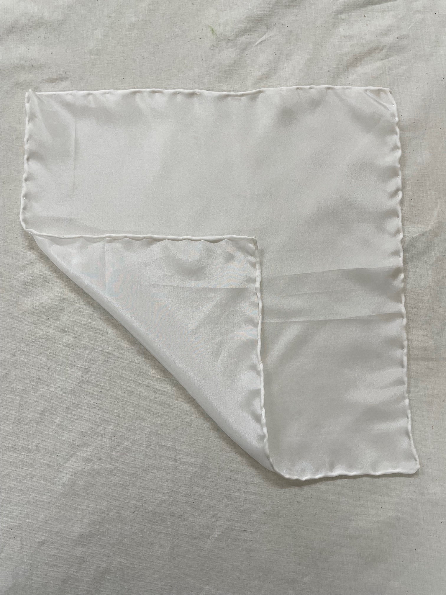Undyed Habutai silk square handkerchief with a corner folded over on a matching background