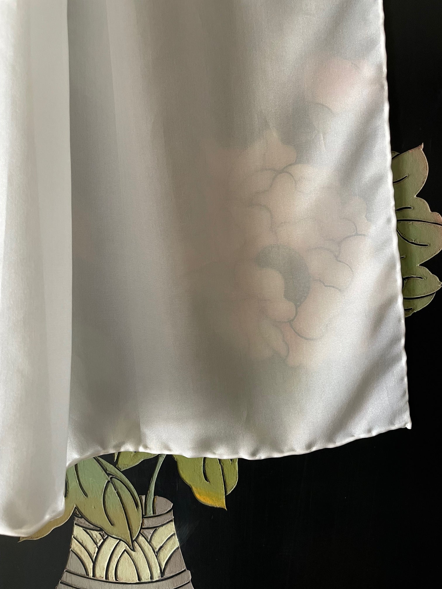 Undyed white habutai silk scarf against a floral design on a black background
