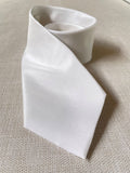 Undyed Habutai silk tie roll on a textured beige background
