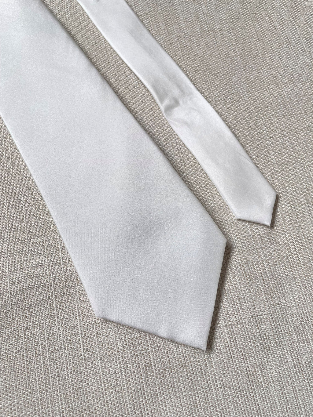 Undyed Habutai silk tie back and front on a textured beige fabric background