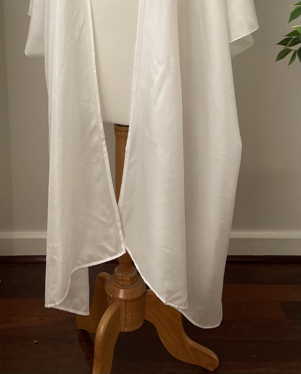 Undyed Kimono hem section fabric draped over a wooden stand against a neutral wall.