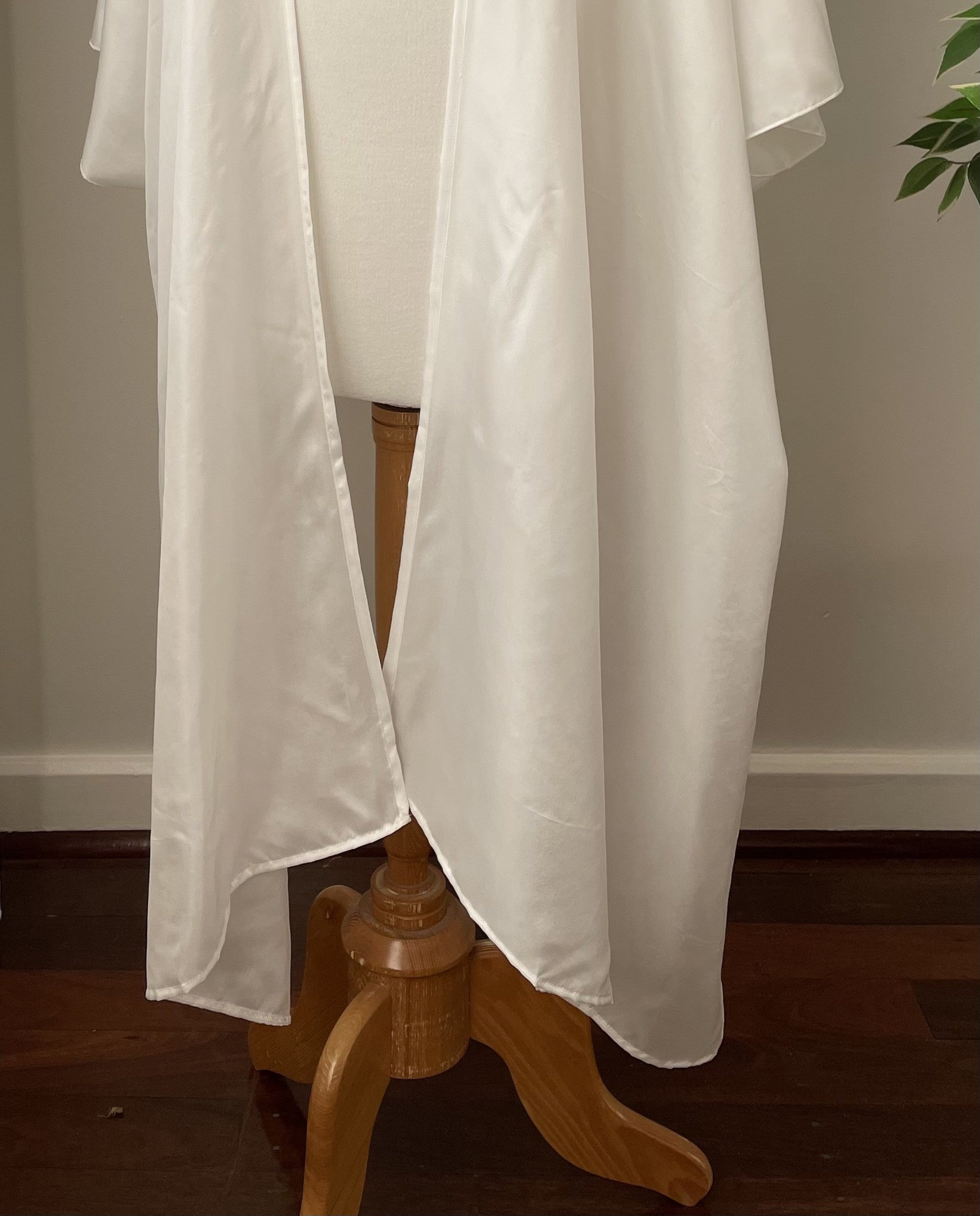 Undyed Kimono hem section fabric draped over a wooden stand against a neutral wall.