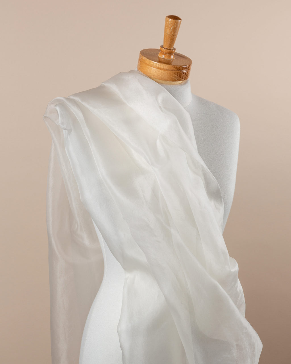 Undyed silk organza white fabric draped over a mannequin on a beige background