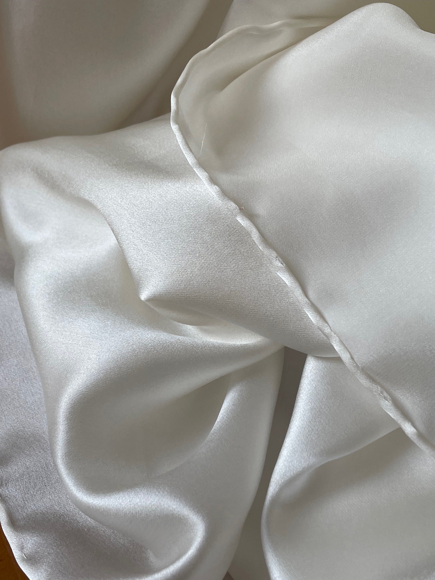 Close-up of undyed white silk satin crepe fabric with a soft texture