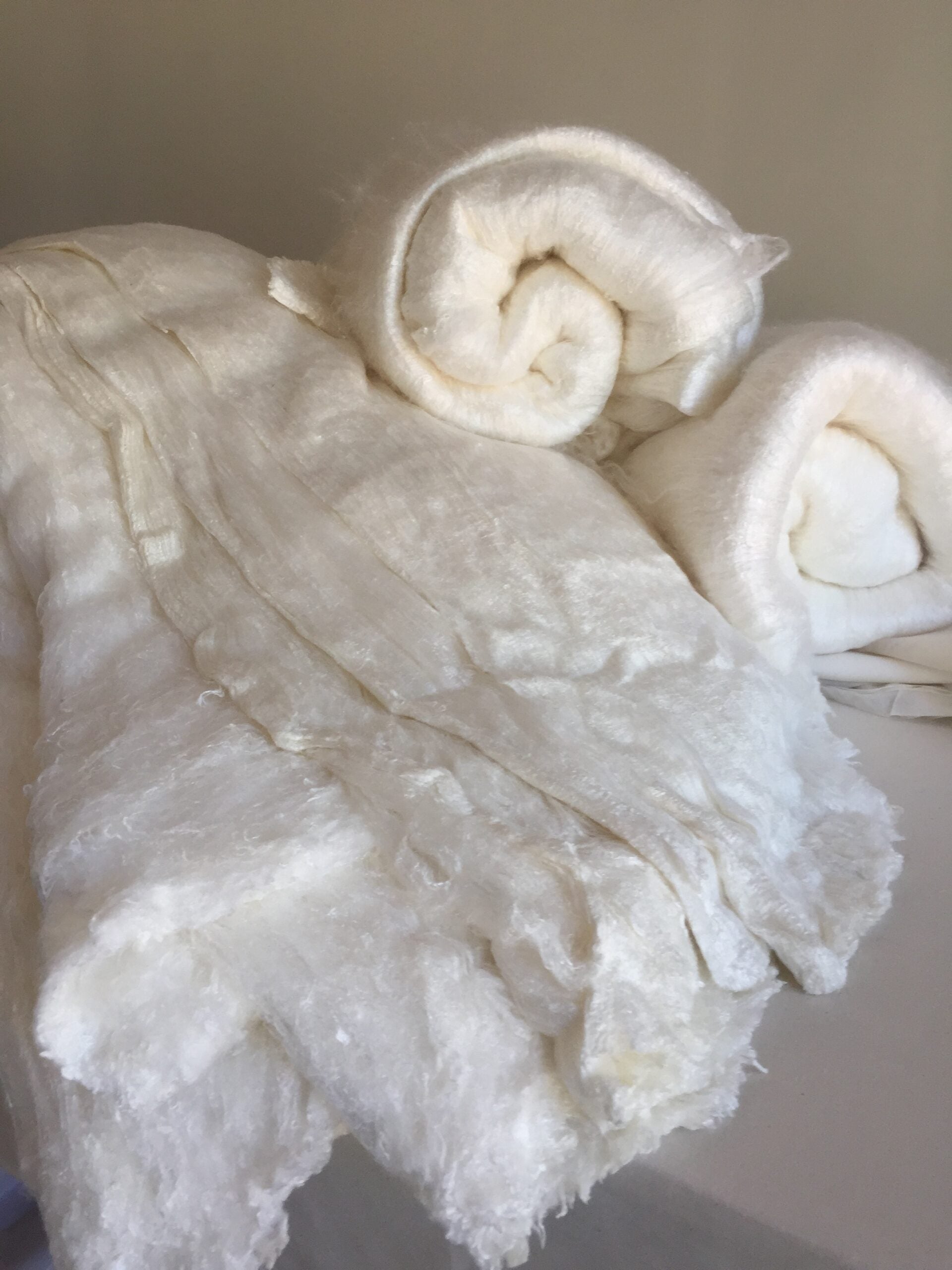 Close-up of white silk laps with a textured surface on a neutral background