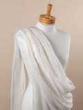 Undyed silk fabric draped over a mannequin on a beige background
