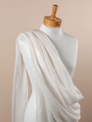Undyed silk fabric draped over a mannequin on a beige background