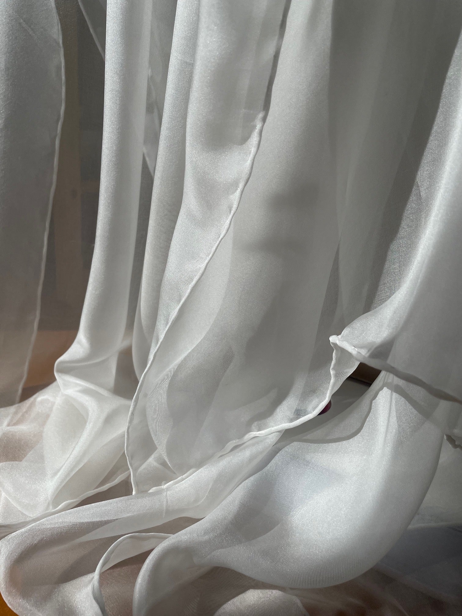Close-up of undyed white silk chiffon scarf with folds and light reflections