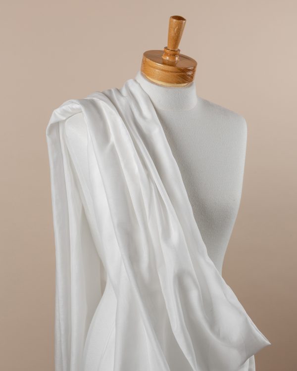 Undyed silk cotton voile fabric draped over a mannequin on a beige background