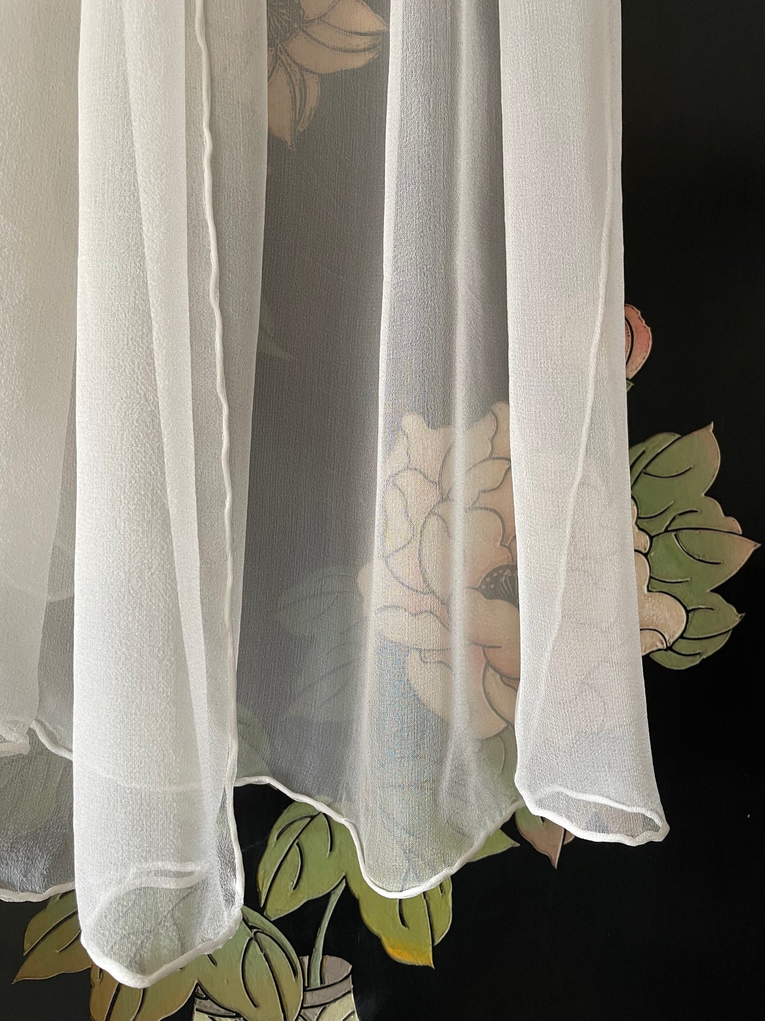 Sheer undyed white silk gauze scarf on a floral-patterned background