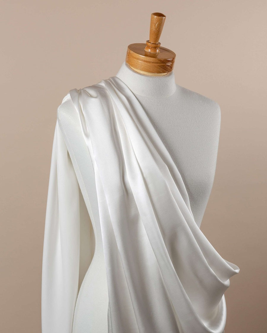 Undyed silk satin crepe fabric draped over a mannequin on a beige background