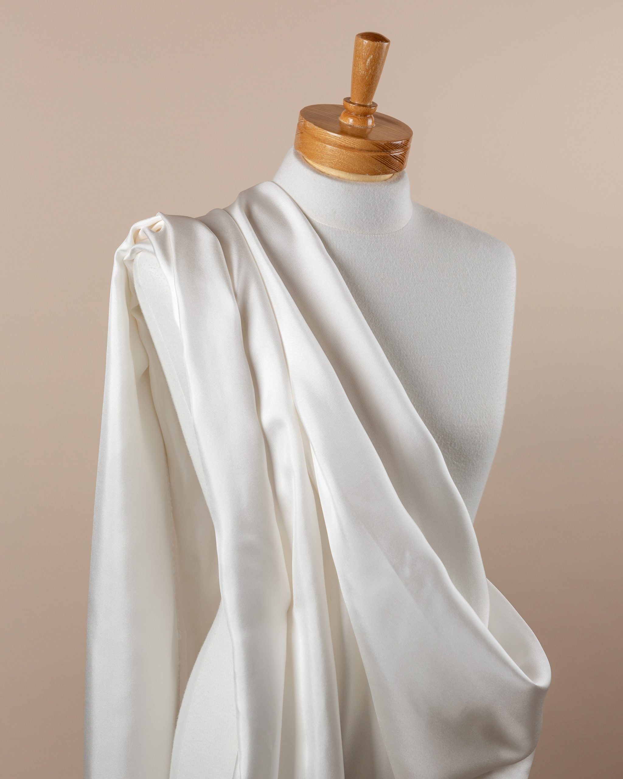 undyed silk twill fabric draped over a mannequin with a wooden head on a beige background