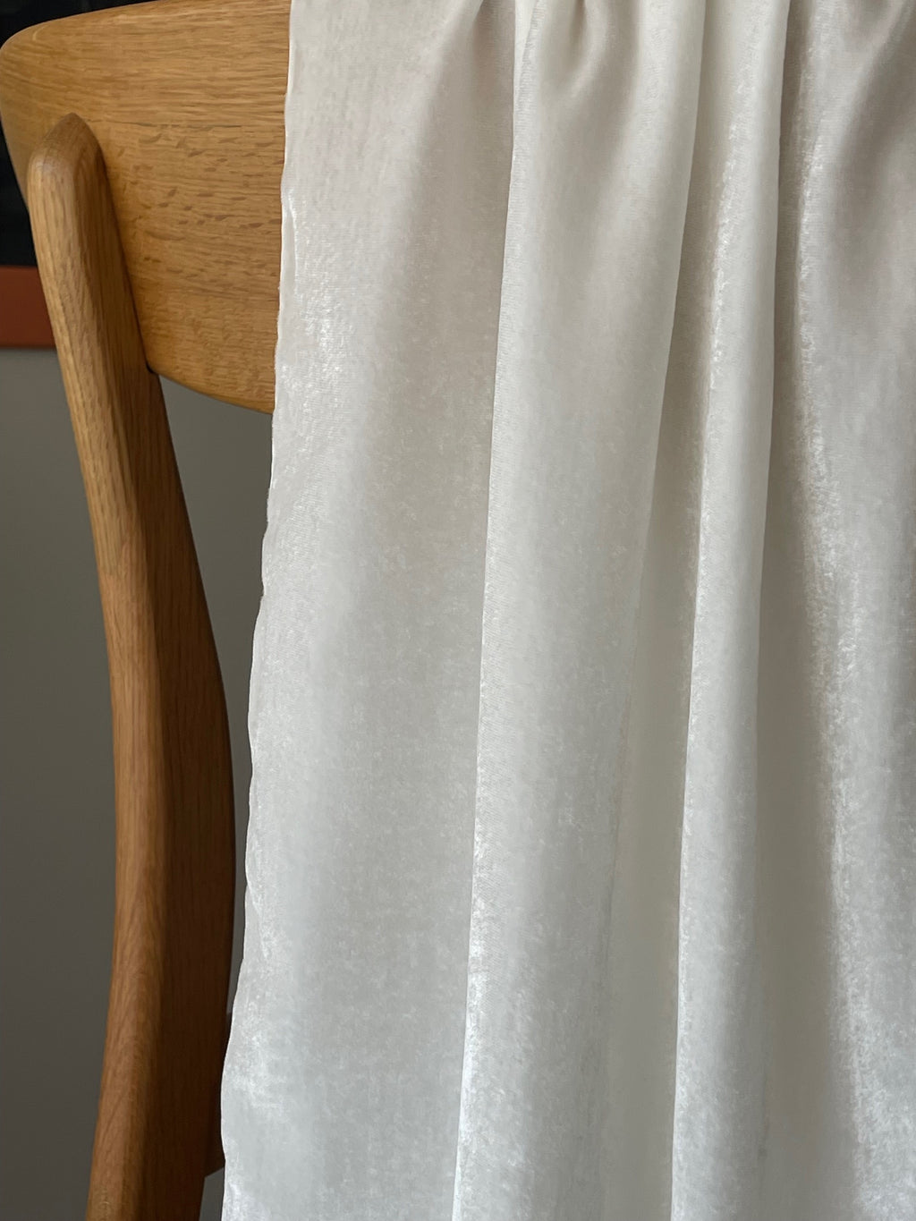 Close-up of a wooden chair with an undyed Silk Viscose Velvet scarf draped over it against a neutral background