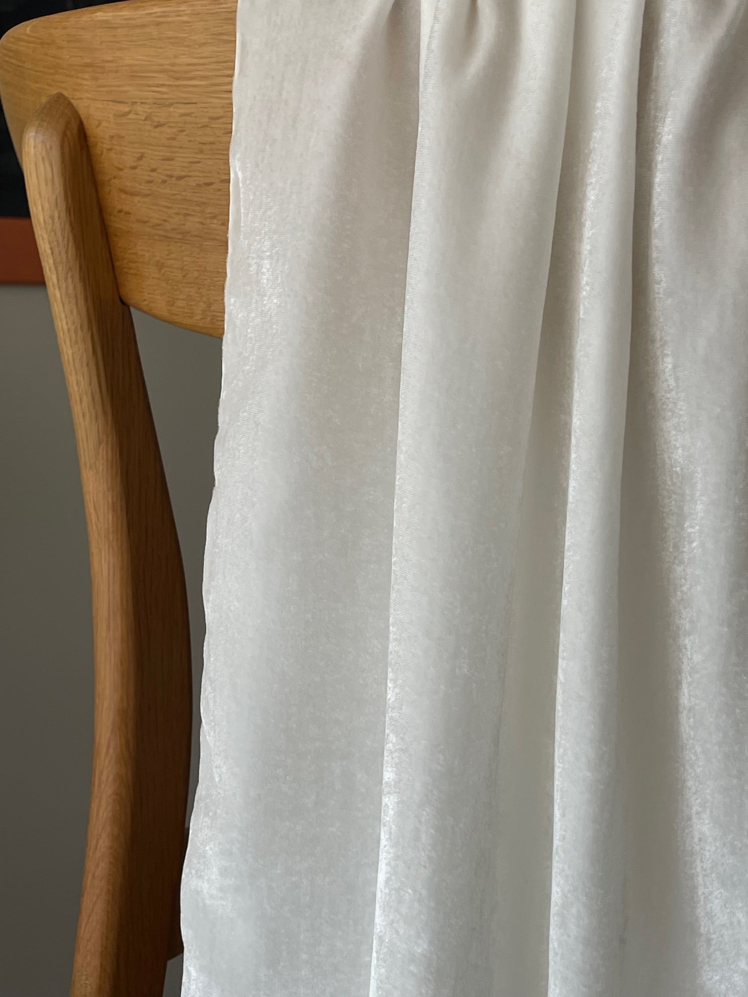 Close-up of a wooden chair with an undyed Silk Viscose Velvet scarf draped over it against a neutral background