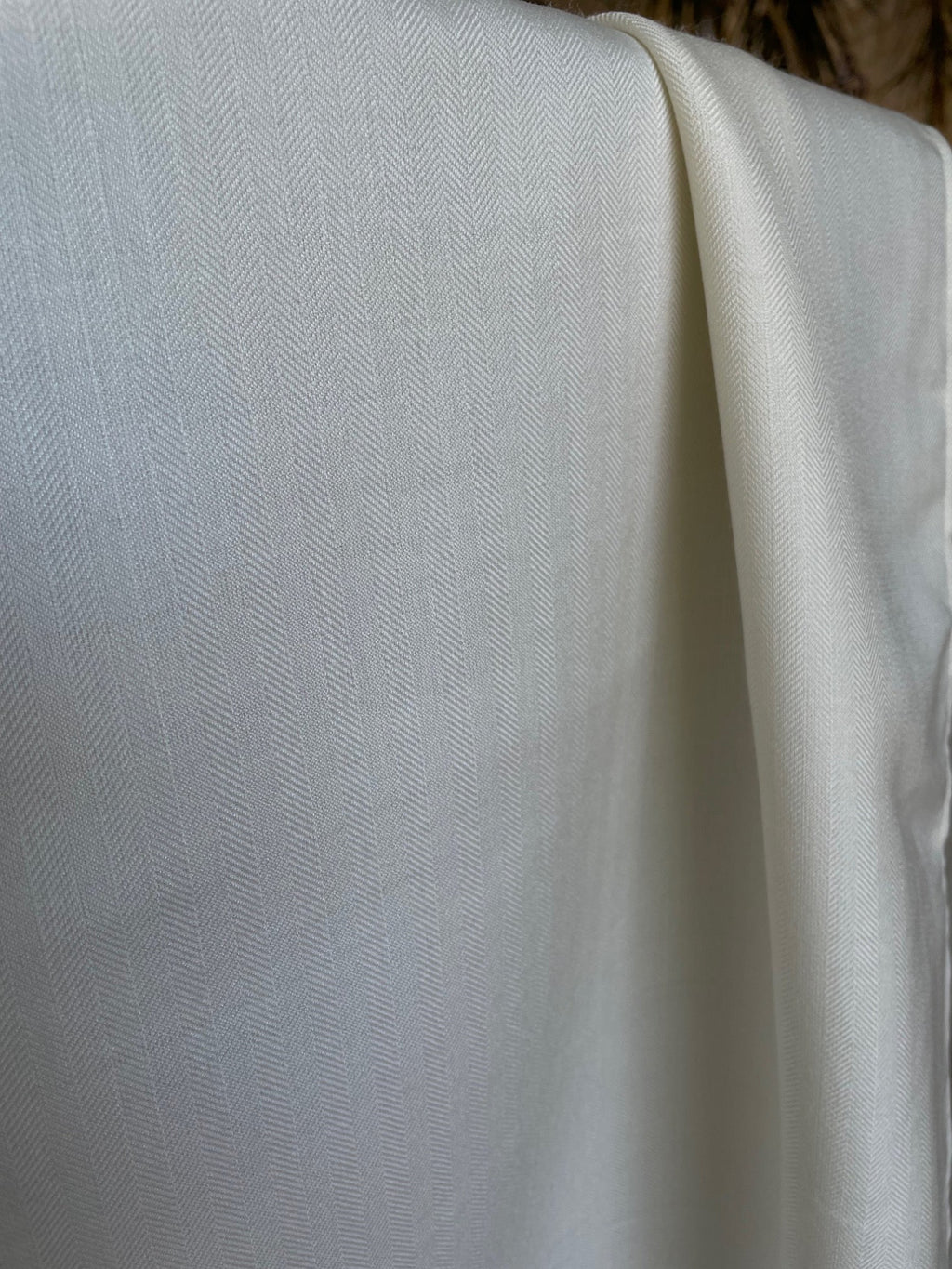 Close-up of undyed silk wool fabric draped softly with a subtle pattern