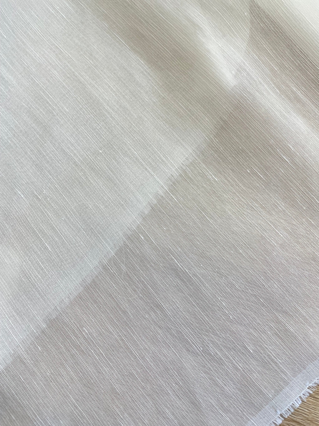 A close-up of a white undyed silk linen fabric with a subtle diagonal textured pattern.