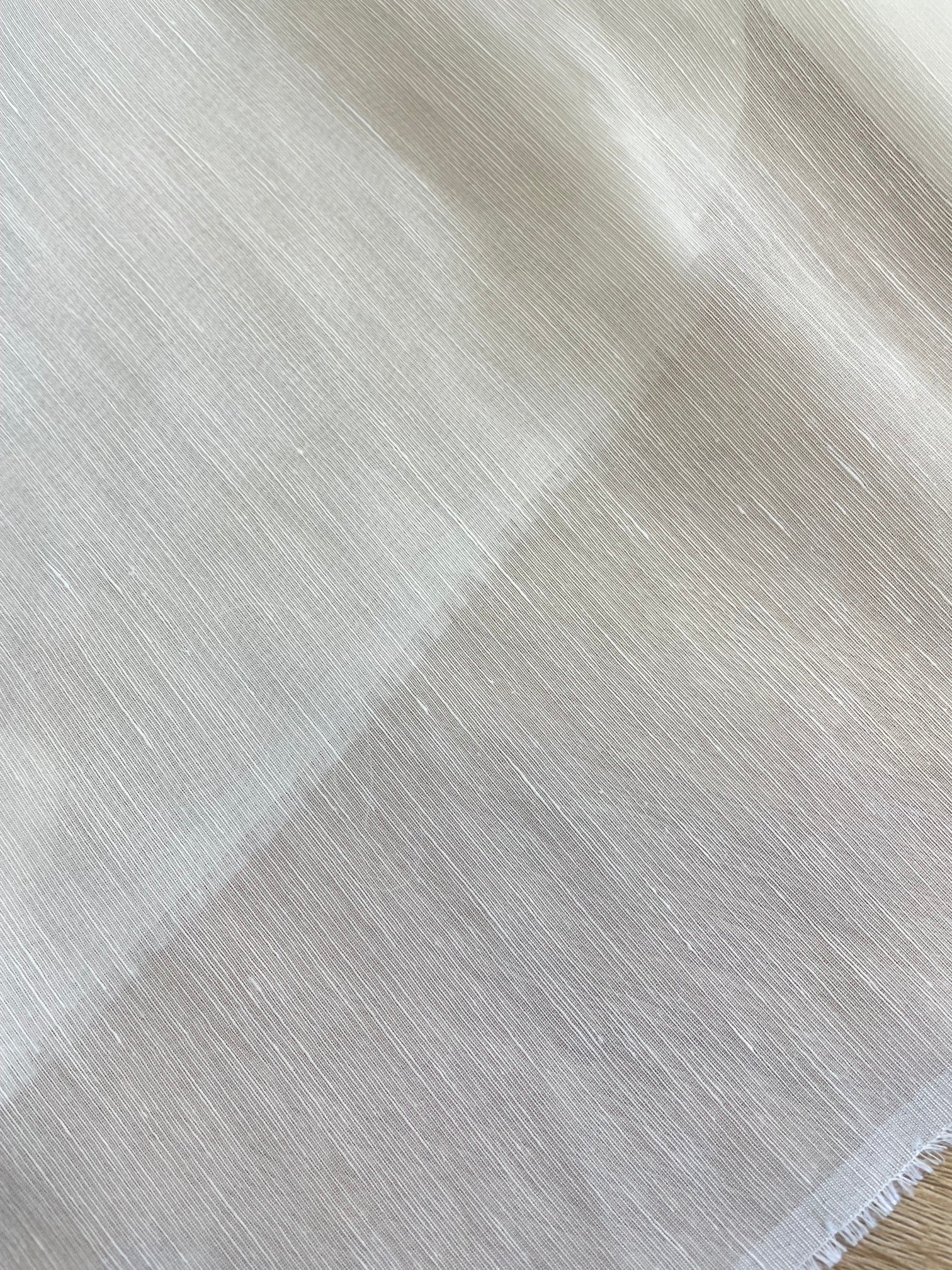 A close-up of a white undyed silk linen fabric with a subtle diagonal textured pattern.