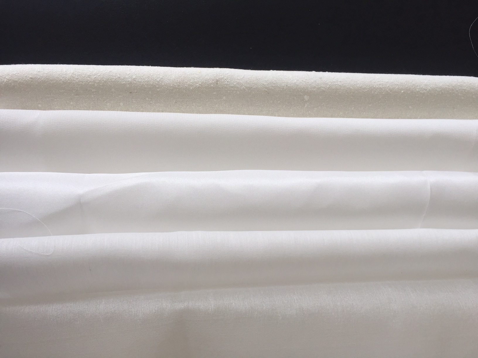 Close-up of undyed silk fabrics with a dark background
