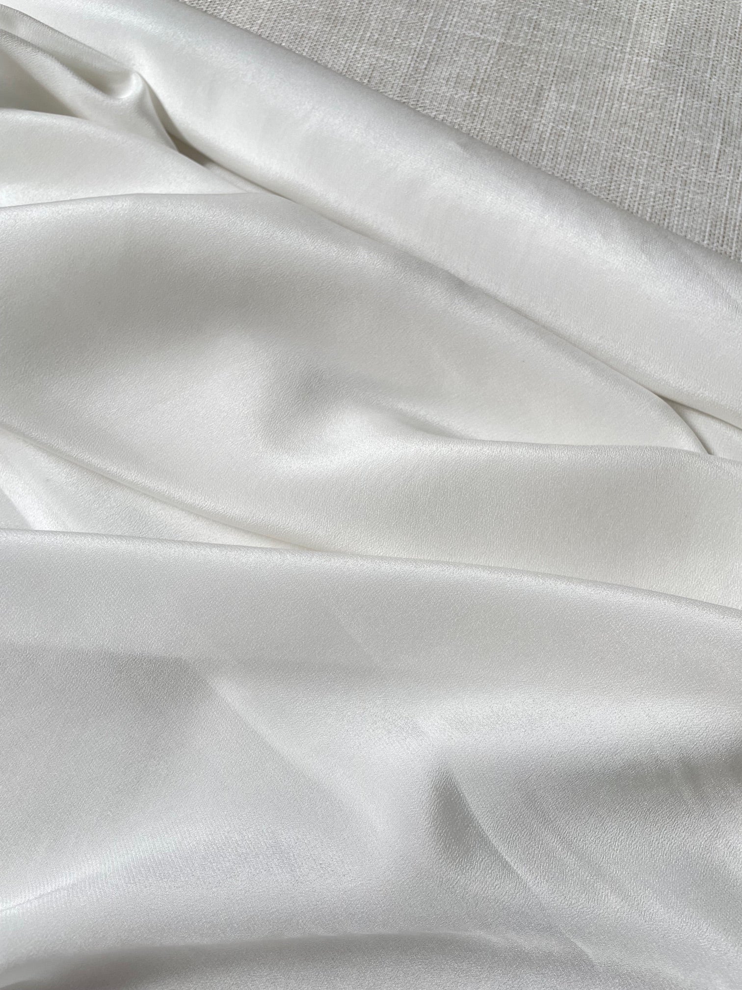 Close-up of undyed crepe de chine fabric with a textured gray background