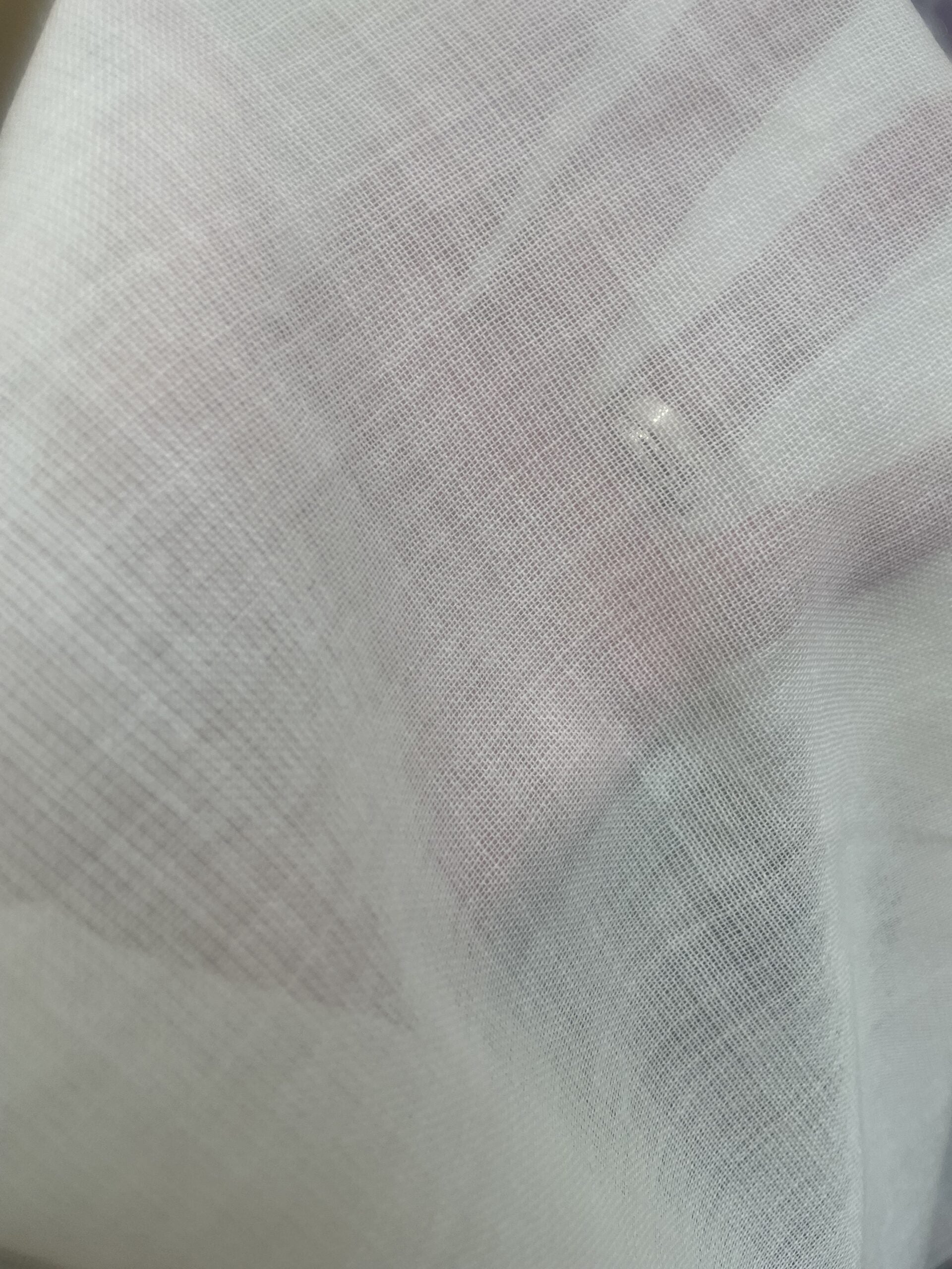 Close-up of a textured undyed finished wool gauze fabric showing its sheerness