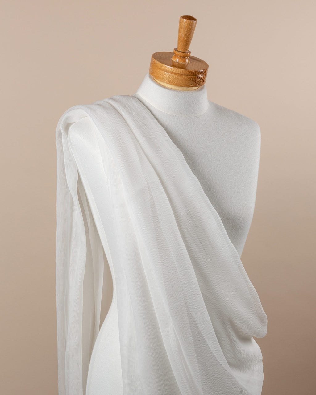 Mannequin draped with undyed silk crinkle chiffon fabric against a beige background