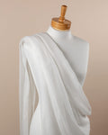 Mannequin draped with undyed silk crinkle chiffon fabric against a beige background